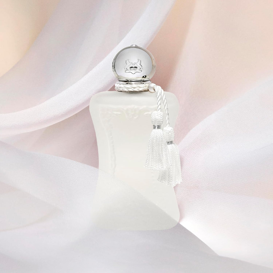 White perfume bottle with tassel on a soft pink background