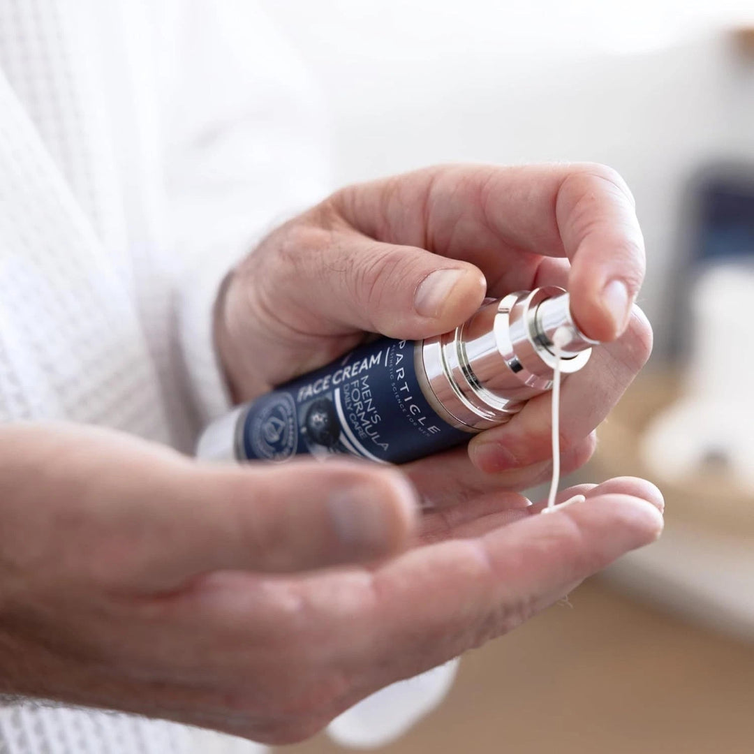particle-mens-face-cream-bottle-held-blurred-background.jpg